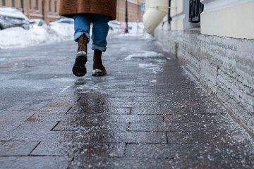 Selective focus on technical salt grains on icy sidewalk surface in wintertime, used for melting...