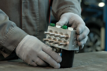 Anti-lock ABS system. An auto mechanic prepares a new ABS solenoid valve unit for installation and...