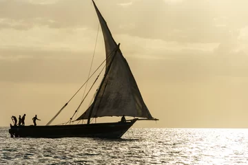 Fotobehang dhow traditional sailing vesssels of zanzibar tanzania at dusk viewed on a calm dusk evening  © mikefoto58