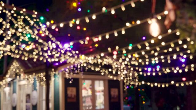 Blurred flickering lights of hanging garlands for New Year christmas street decorations at night, merry Christmas and happy New Year mood and defocused twinkling lights