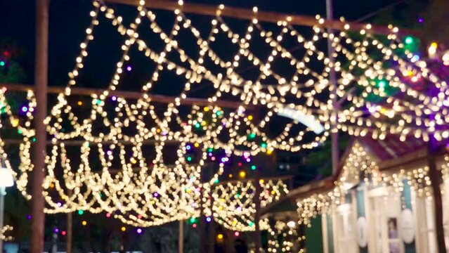 Blurred flickering lights of hanging garlands for New Year christmas street decorations at night, merry Christmas and happy New Year mood with defocused twinkling lights merry