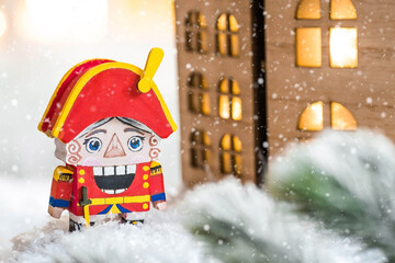 Naklejka premium A toy soldier Nutcracker and walnuts on a Christmas background with a garland. Tchaikovsky's ballet. Christmas New Year card 2024.