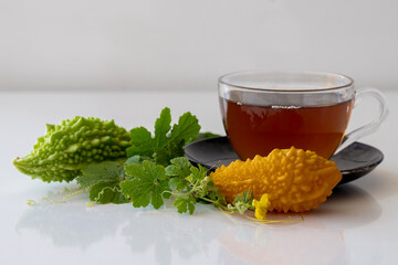 Bitter gourd or bitter melon tea in transparent cup and fresh bitter gourd with green leaf isolated...