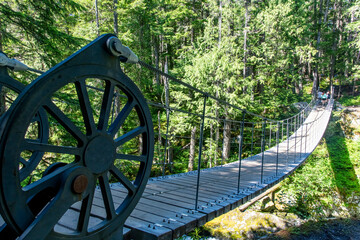 View over Train Wreck Bridge, Whistler, BC, Canada with anchor frames designed to look like locomotive wheels on the Sea To Sky Trail leading to the colorful train wreck box cars from 1956 accident