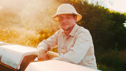 Close up portrait of attractive professional male beekeeper wearing special clothes looking at...