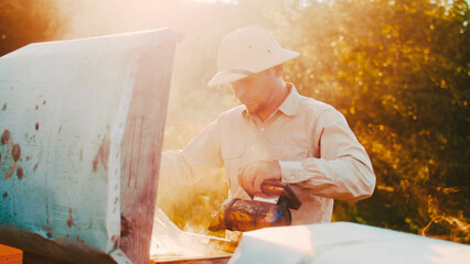 Portrait of young professional beekeeper in special uniform looking at camera and smiling....