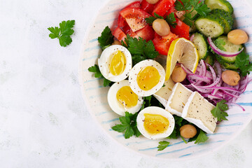 Breakfast. Greek salad and boiled eggs. Fresh vegetable salad with tomato, cucumbers, olives, arugula and cheese. Trendy food. Top view, flat lay
