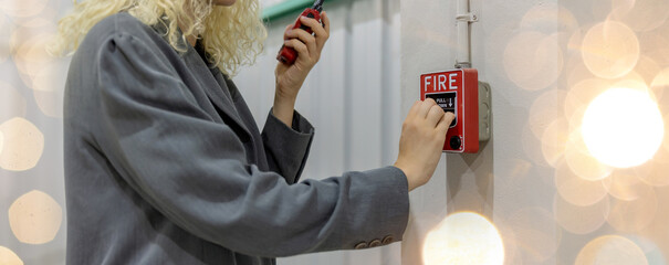 Foreman or worker pushing fire alarm on the wall. A fire! or Emergency case at the factory building. Emergency of Fire alarm or alert or bell warning equipment - obrazy, fototapety, plakaty