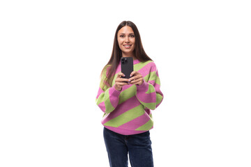 young slender caucasian woman with straight black hair dressed in a striped pink pullover communicates in social networks using a smartphone