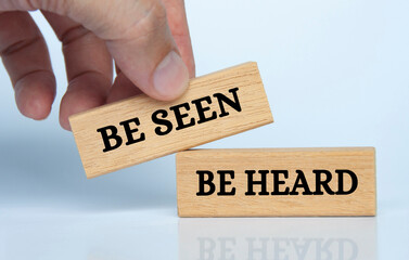 Hand holding wooden block with text be seen and be heard. Business concept.