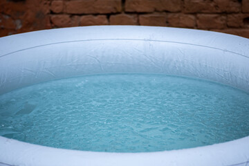 Portable plastic inflatable tub in a garden ready for ice bathing in the cold water filled with ice cubes. Wim Hof Method, cold therapy, breathing techniques, yoga and meditation