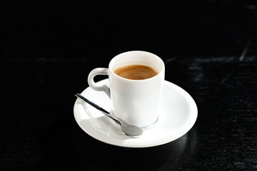 Espresso coffee. Close up photo of a white ceramic pot filled with fresh espresso ristretto coffee against dark wooden table.