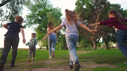 Fototapeta premium children in the park. boys and girls run through the green park laughing. spending time with friends. happy family kids dream concept lifestyle