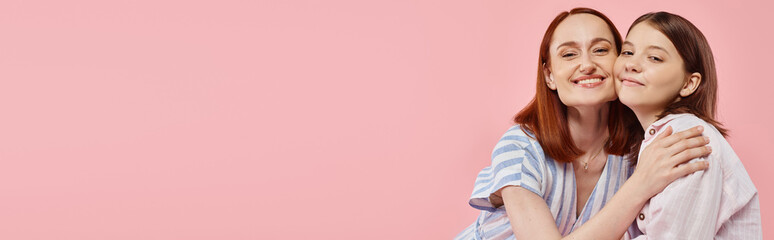 joyful and trendy woman with teenage daughter embracing and looking at camera on pink, banner