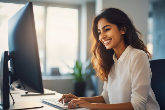 Portrait of Enthusiastic Hispanic Young Woman Working on Computer in a Modern Bright Office.