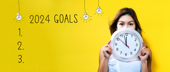 2024 goals with young woman holding a clock showing nearly 12 - obrazy, fototapety, plakaty