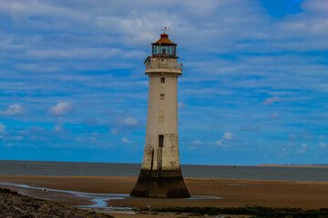 An historic Lighthouse on the beach with the sea in the background.