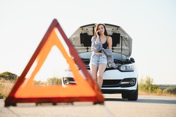 Young sexy woman with broken car calling on the cell phone.