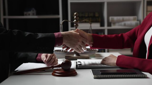 Legal consultant makes agreements with clients by shaking hands and signing contracts and agreements. Female lawyer signing contract with client and shaking hands in office