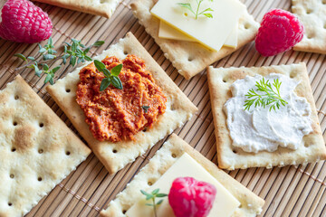 Various kind of salty crackers with vegan meat and vegan cream cheese decorated with fresh herbs and raspberries. Vegan food concept.