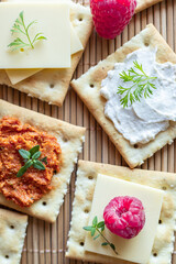 Close up o Various kind of salty crackers with vegan meat and vegan cream cheese decorated with fresh herbs and raspberries. Vegan food concept.