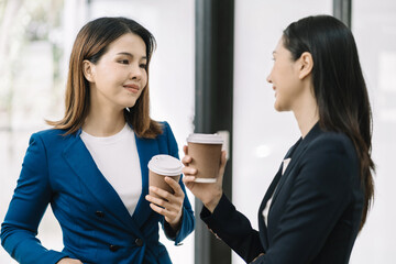 female colleague of half Asian descent holds a cup of coffee and smiles happily.