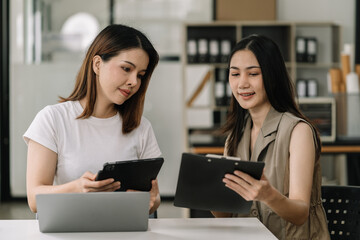 Business, technology and office concept - two businessmen with laptop, tablet pc computer and papers having discussion in modern office.
