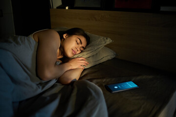 Woman sleeping near alarm ringing on smart phone at home