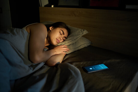Woman sleeping near alarm ringing on smart phone at home