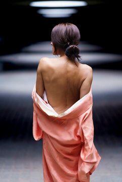 Mature woman wearing backless kimono and walking in spotlight
