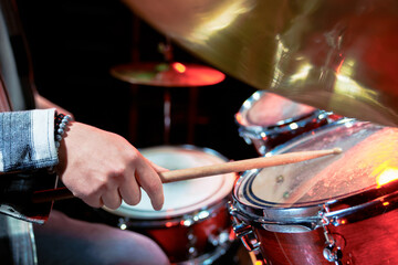 Male hands playing a drum kit on stage.