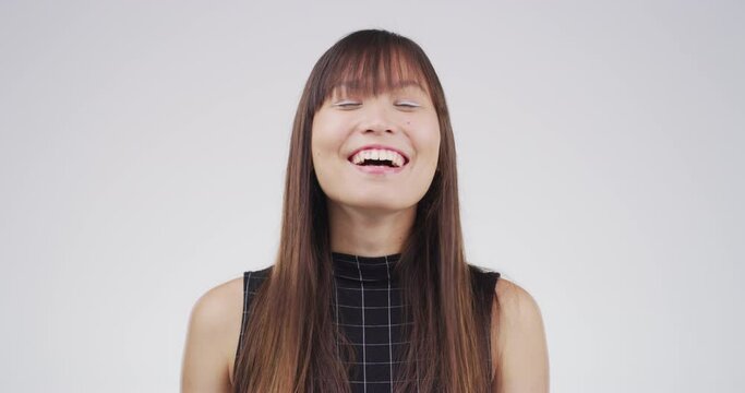 Face, laughing and asian woman in studio with feel good mood, mindset or positive attitude on grey background. Comic, smile and portrait of female model with reaction to crazy, funny or comedy joke