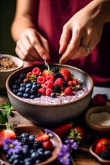A woman preparing a smoothie bowl with berries, yogurt and seeds