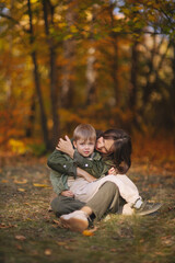 Naklejka na ściany i meble Mom and children walk in the park and enjoy the beautiful autumn nature. Happy family on an autumn walk. Natural Park. Family active holiday concept.