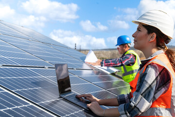 Young engineer inspect installation of solar panels installed check  with blueprint on the field,...