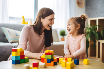 Happy mother and little girl playing with blocks on the floor.