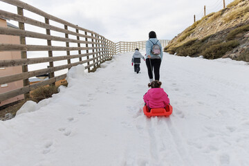 Family playing in the snow with a sled