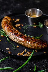 Grilled sausage on a dark plate with sauce