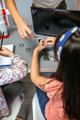 Unrecognizable female teacher helping girl student to assemble electrical circuit in a robotics class. Elementary technological education concept.