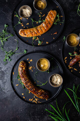 Grilled sausage on a dark plate with sauce