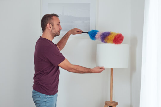 Man cleaning apartment with dusting broom.