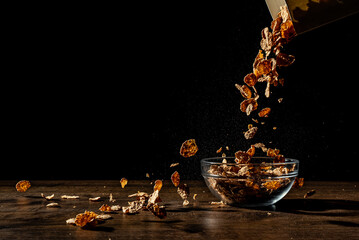 Cornflakes sprinkle on a bowl on black background
