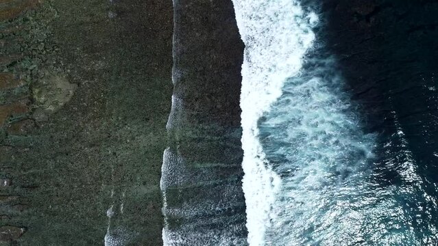 An aerial perspective looking straight down at the ocean with waves rolling in