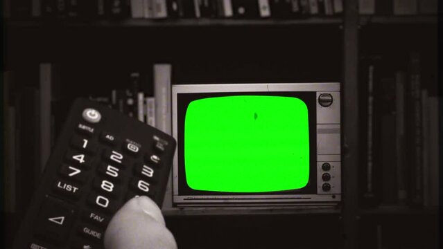 Changing Channels Green Screen Television Remote Control Retro TV Zoom In. Remote control changing channels on an old vintage green screen television, zoom in. Old film texture