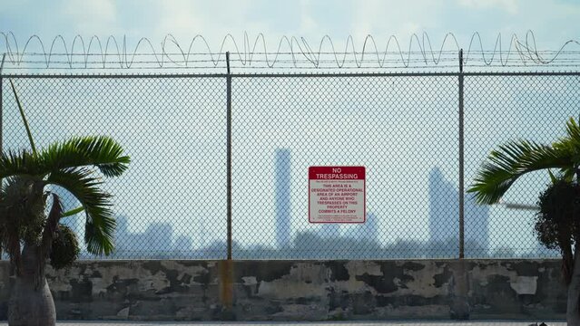 Barbed wire fence surrounding Miami airport runway as protective security measure against trespassing violation. Safety of air traffic