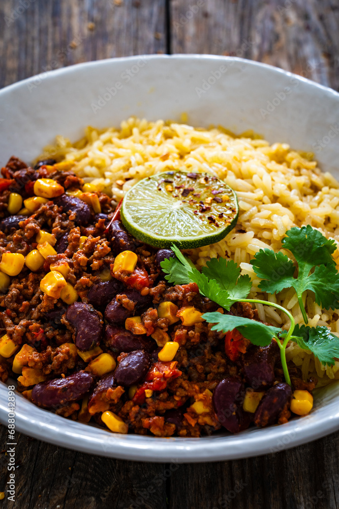 Wall mural Chili con carne with rice on wooden table