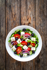 Greek style salad - fresh vegetables with feta cheese on wooden table
