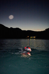 A determined professional triathlete undergoes rigorous night time training in cold waters,...