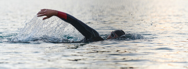 A professional triathlete trains with unwavering dedication for an upcoming competition at a lake,...