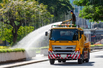 Truck with a water tank waters plants and flowers from a fire hose, a city park worker
